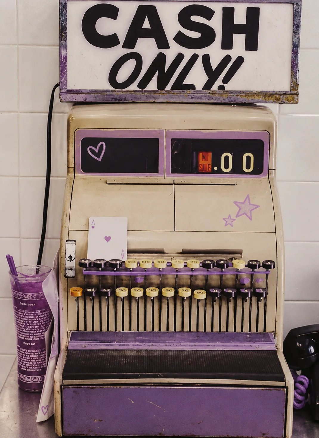 A vintage cash register with a Cash Only sign, painted lavender